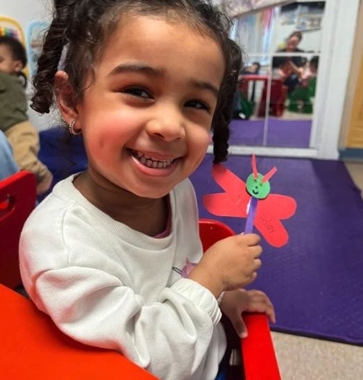 Smiling child holding a flower craft