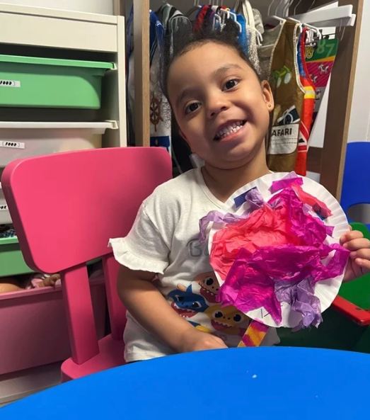 Smiling child holding up a tissue-paper collage they made