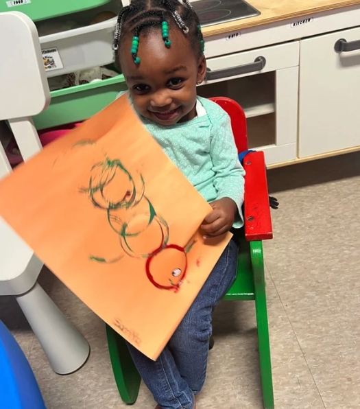 Child proudly holding up their own drawing
