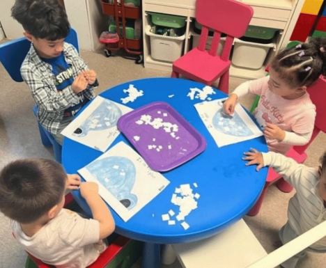 Group of children working on an art activity around the blue table
