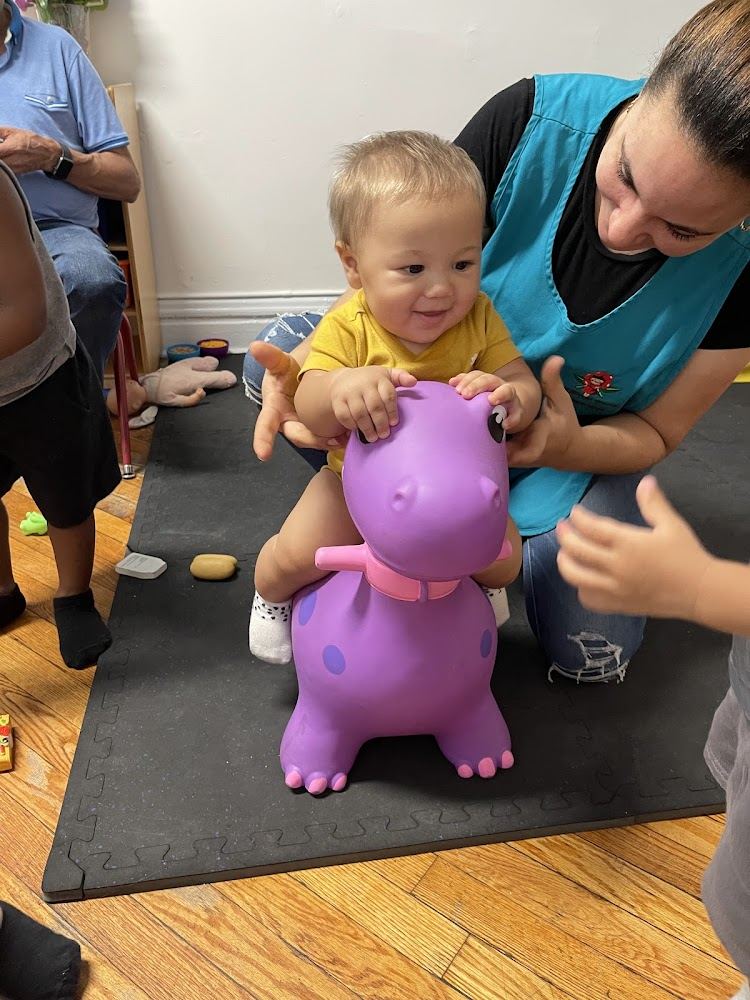 Staff member supporting a baby on a bouncy toy on a padded mat