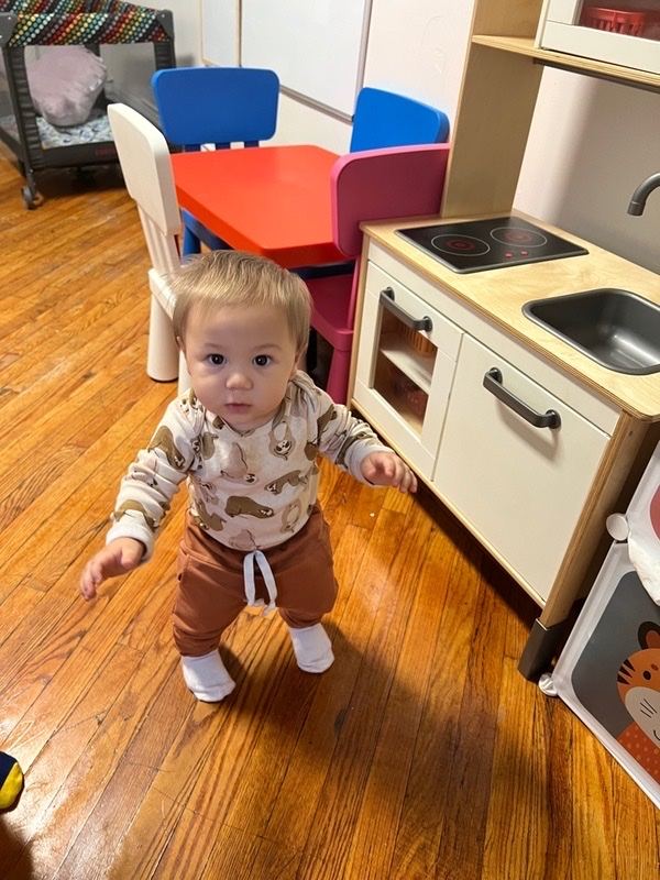 Baby standing on their own beside the play kitchen