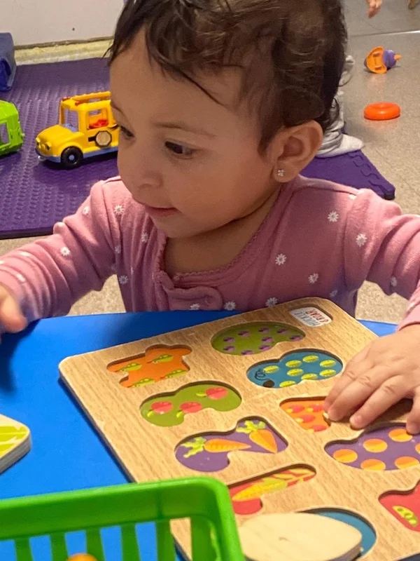 Toddler working on a wooden shape puzzle at a low table