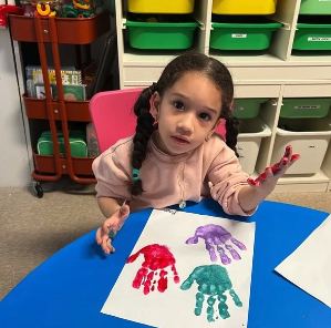 Child showing a finished red and blue handprint picture