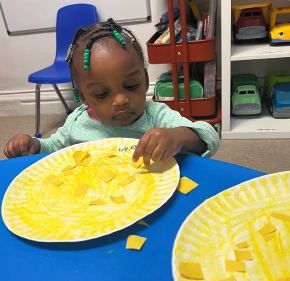 Child arranging yellow tissue paper on a plate
